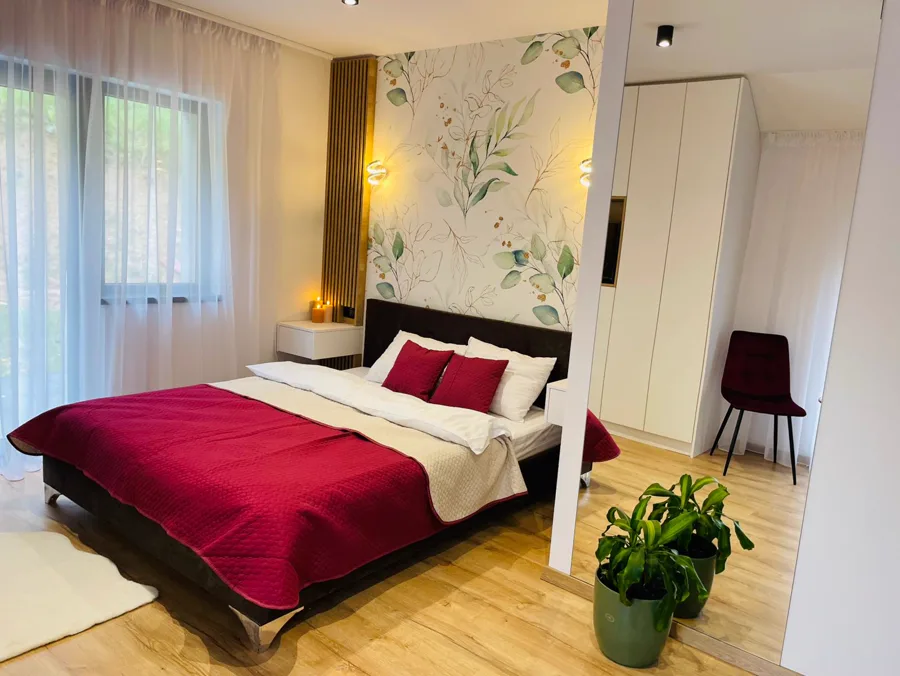 Bedroom with botanical wallpaper and burgundy bed linen